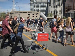 Sasha Grbich with large microphone, walking across the road