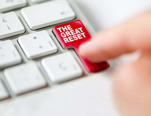 Finger pushing red button marked 'The Great Reset'.