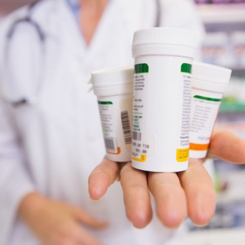 pharmacist holding out pill bottles